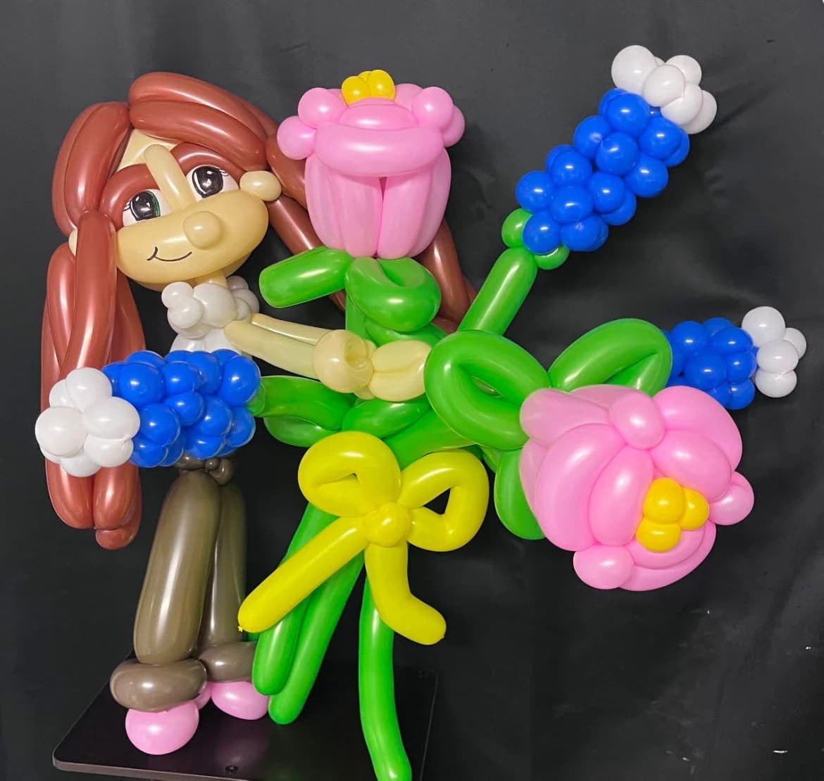 Balloon caricature holding a bouquet of pink and blue flowers