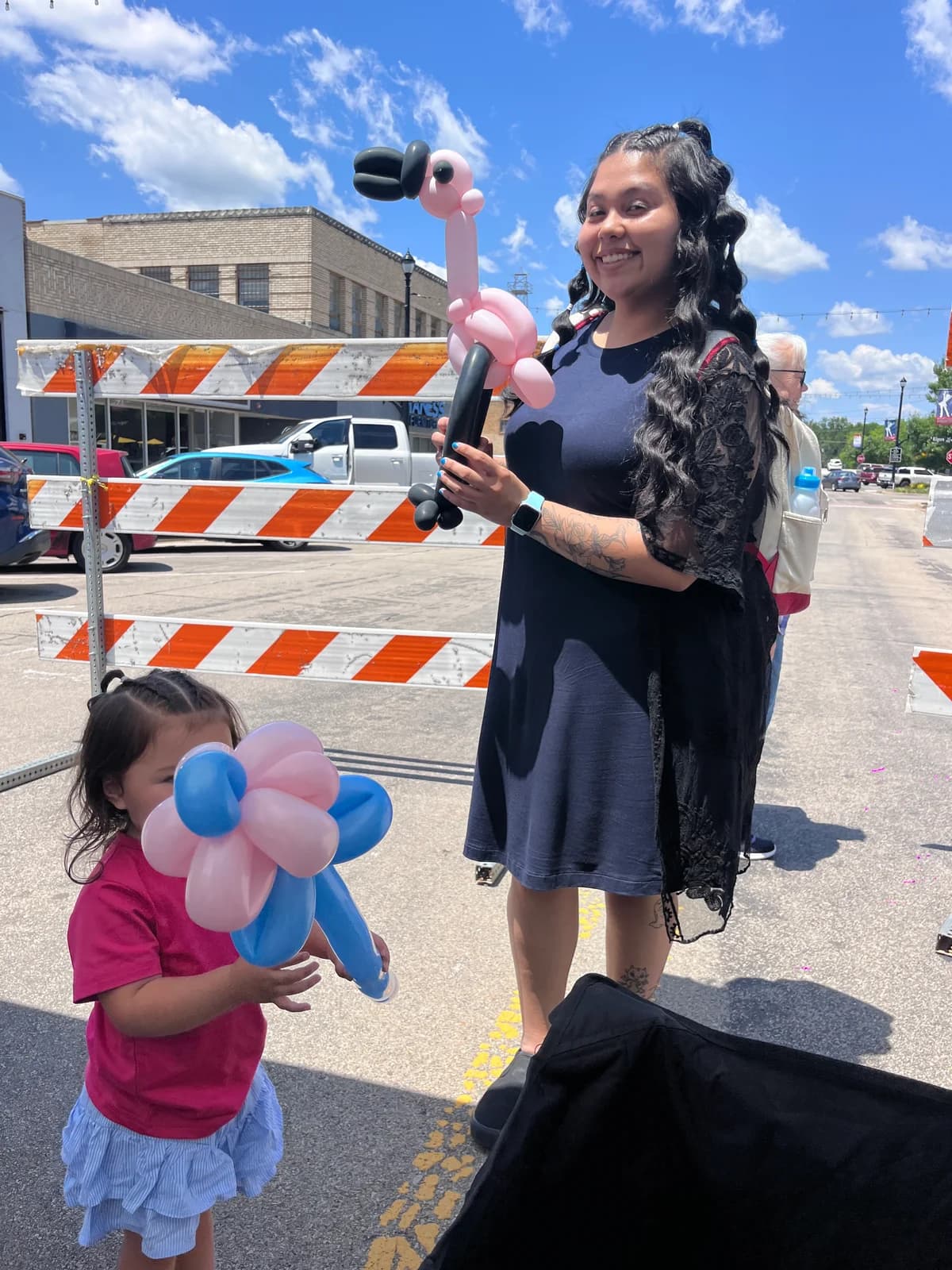 Guests holding a pink balloon flamingo and a flower at an outdoor event