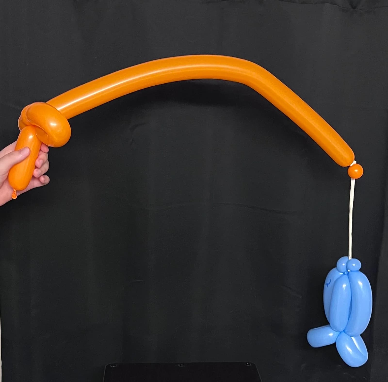 Orange balloon fishing pole with a blue balloon fish